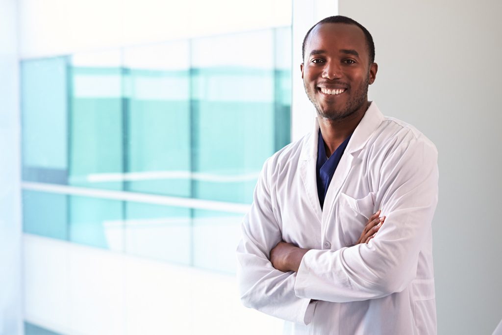 Man crossing his arms, wearing a lab coat and smiling