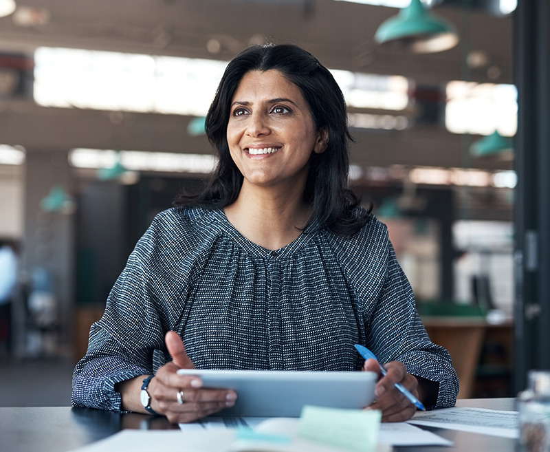 Women smiling and reading a detailed report on an iPad