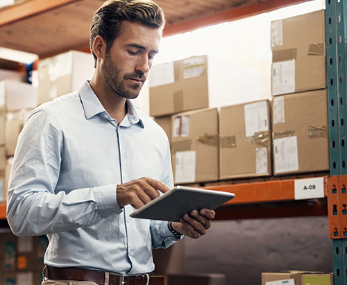 Man standing in warehouse using iPad
