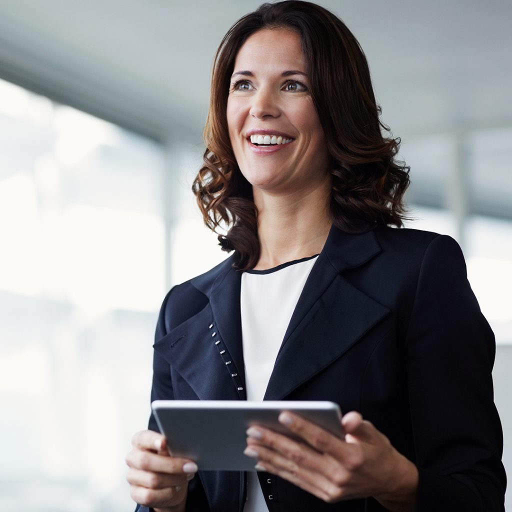 Woman in blue jacket using iPad and smiling